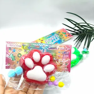 Détail en gros plan d'un jouet antistress patte de chat dans son emballage coloré avec pompons.