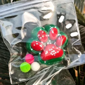 Macro view of Christmas themed cat paw squishy toy in clear packaging with colorful poms
