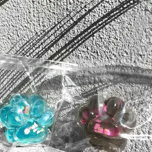 Détail de squishies patte de chat bleus et noirs dans un emballage plastique transparent