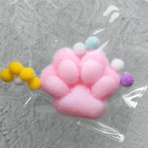 Macro detail of a pink plush cat paw squishy toy inside a clear plastic protective bag.