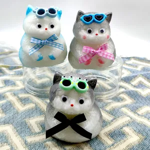 Primer plano de tres lindos juguetes squishy de gatos con gafas de sol y lazos de tela.