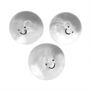 Detailed view of three silver stress relief squeeze toys with smiley faces on white background