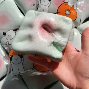 Hand squeezing a pale green slow rebound toast squishy toy with pink speckles