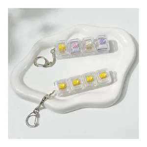 Detailed macro shot of 4-key mechanical switch tester keychain set on a white tray