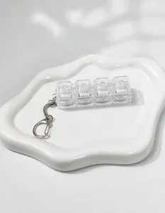 Close-up of 4-key transparent mechanical switch tester keychain on white tray