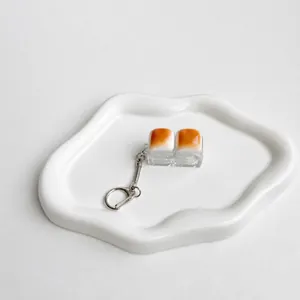 Detail view of a caramel bread-shaped fidget switch tester keychain on a ceramic tray