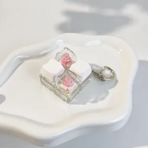 Close-up view of 2x2 custom mechanical keycaps with cat and rose designs on a keychain.