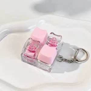 Detailed view of a pink and clear mechanical switch fidget toy keychain on a wavy ceramic tray