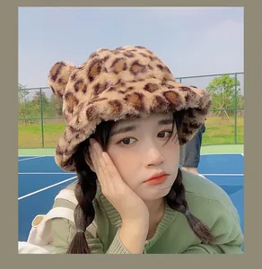 Close-up of a cute fuzzy leopard print bucket hat with bear ears worn by a female model outdoors