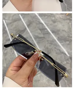 Close-up of rimless rectangular sunglasses with gradient grey lenses and gold metal temples.