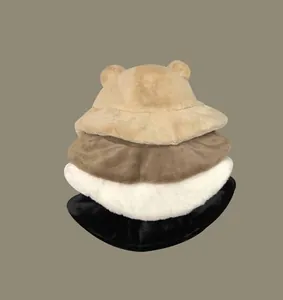 Stack of four fuzzy bear ear bucket hats in tan, brown, white, and black colors.