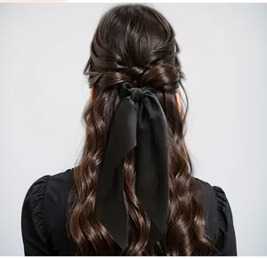 Back view showing black satin knotted hair ribbon with long streamers on wavy brown hair