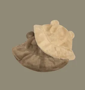 Close-up macro view of two plush furry bucket hats featuring cute 3D bear ears in beige and brown