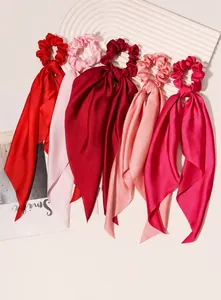 Detailed view of satin knotted hair scrunchies with long ribbons in pink shades