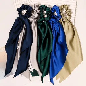 Detail of five solid color satin scrunchies with long elegant ribbons for hair styling