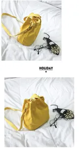 Detail view of minimalist yellow canvas bucket bag with stylish lifestyle props