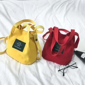Close-up of minimalist yellow and red canvas bucket bags with letter embroidery detail