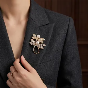 Elegant gold-tone dragonfly brooch with white pearls and crystals on a grey blazer