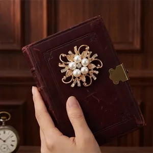 Elegant golden flower brooch accessory with five pearls on a vintage retro notebook.