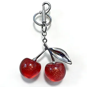 Elegant translucent red cherry keychain with gold glitter for handbags and car keys.