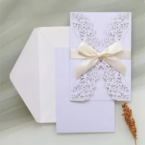 Detailed view of white laser cut wedding invitation with elegant ribbon bow