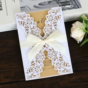 Detailed view of white laser-cut floral pattern and cream silk bow on invitation card