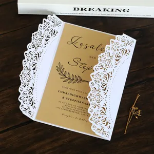Close-up of elegant white laser-cut lace wedding invitation with kraft paper inner.