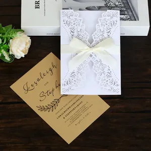 Elegant laser-cut white wedding invitation card featuring a cream satin ribbon bow