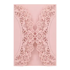 Close-up of pink laser-cut wedding invitation card with intricate floral patterns
