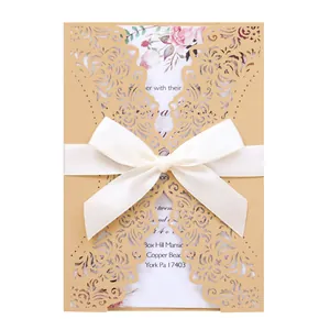 Elegant golden laser-cut wedding invitation with white ribbon bow and floral inner card