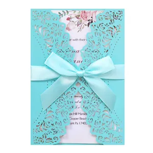 Detailed view of teal laser-cut wedding invitation card featuring elegant satin bow