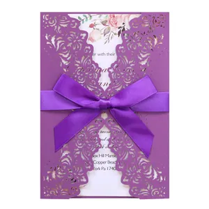 Detailed view of a purple laser-cut wedding invitation card with an elegant ribbon bow.