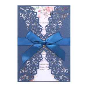 Laser cut navy blue wedding invitation with elegant floral insert and blue ribbon.