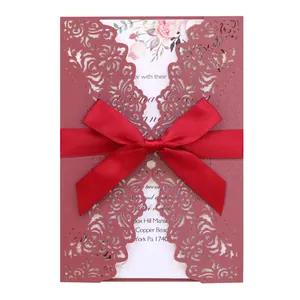 Elegant burgundy laser-cut wedding invitation card with a red satin ribbon bow detail.