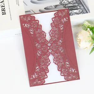 Detailed view of intricate laser-cut floral pattern on burgundy wedding invitation card