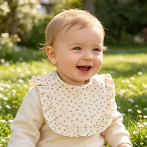 Floral ruffled baby bib in soft cream cotton gauze for infant feeding and teething