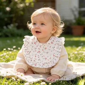 Detail shot showing the floral print and ruffled edges of a soft cotton gauze baby bib