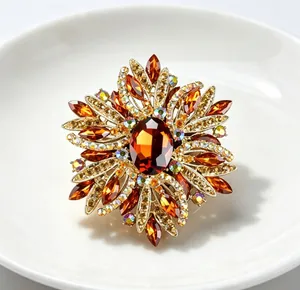 Détail d'une grande broche en cristal ambré avec un motif floral complexe.