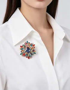 Détail d'une grande broche en cristal vintage colorée portée sur un col blanc.