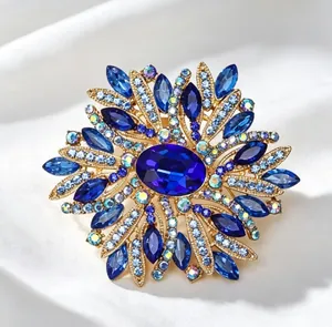 Gros plan d'une élégante broche fleur dorée avec cristaux bleus sur soie blanche
