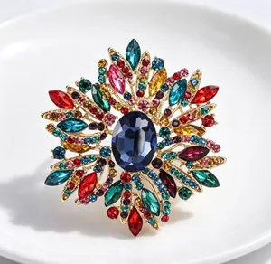 Gros plan d'une grande broche soleil ornée de cristaux multicolores et d'une pierre bleue.