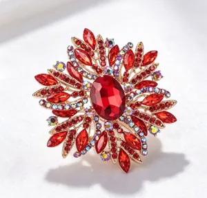 Gros plan détaillé d'une broche dorée ornée de cristaux rouges et de strass irisés.