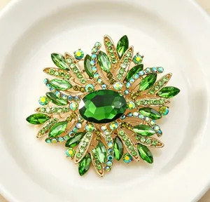 Détail d'une élégante broche fleur en cristal vert avec alliage doré et de faux strass