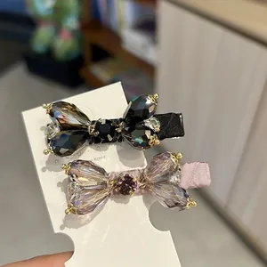 Close-up of elegant pink and black faceted crystal bow hair clips on a display card