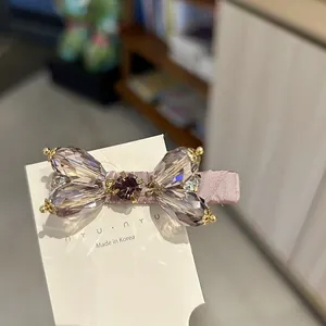 Macro detail of a luxurious pink rhinestone bow hair clip on a white display card