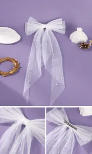 Detailed view of white mesh bow hair clip with pearls and long trailing bridal veil