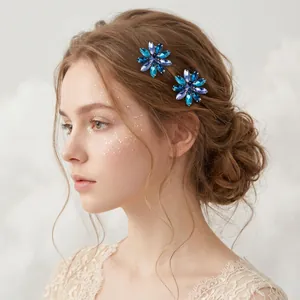 Detail van twee blauwe strass bloem haarspelden gedragen op een zijwaarts kapsel.
