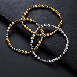 Detailed view of three interlinked elastic beaded bracelets in gold and silver finish