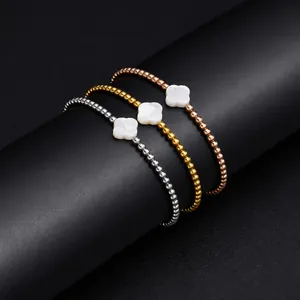 Detail view of three mixed-metal beaded bracelets with shell clover charms.