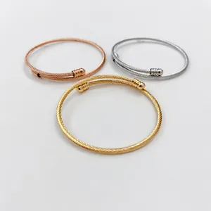 Detailed view of three stainless steel wire bangles in gold, silver, and rose gold